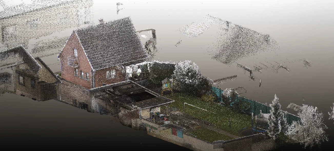Ein 3D-Punktwolken-Rendering eines Wohnviertels, das ein Backsteinhaus, angrenzende Gebäude, grüne Rasenflächen, Gartenbereiche und vereinzelte Bäume zeigt, wobei einige Teile des Bildes im Hintergrund verblassen.